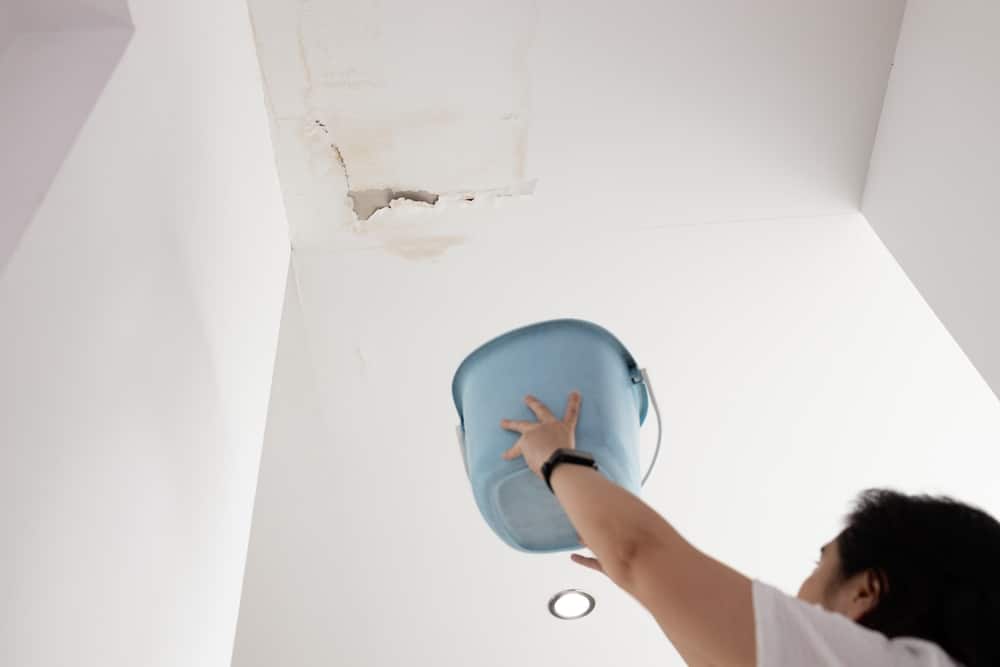 Anxious,Asian,Woman,Standing,Holding,Plastic,Bucket,During,Heavy,Rain,worried Ceiling water leak